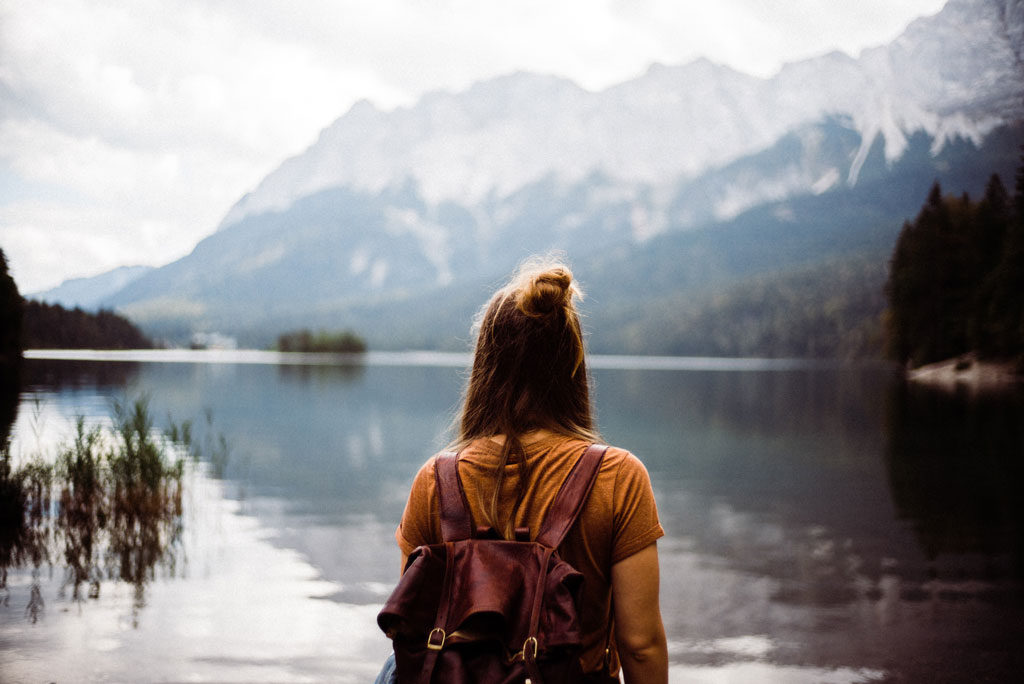 Girl standing in front of a lake with a mountain in the background