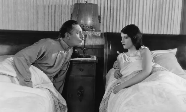 Black and white photograph of a couple sleeping in twin beds