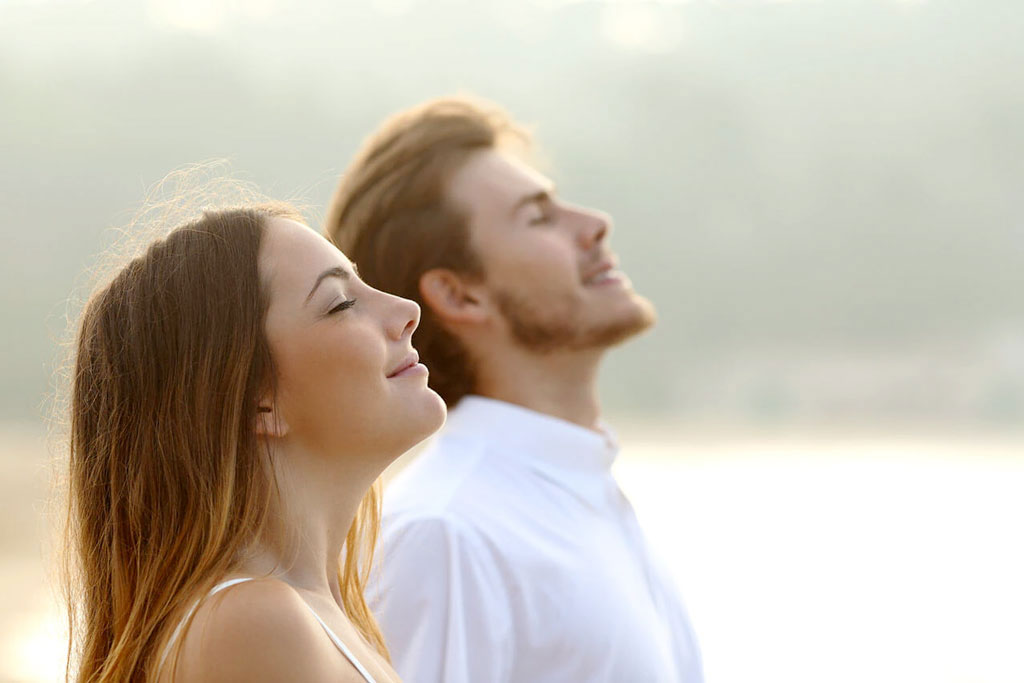 Happy couple taking a deep breath of fresh air