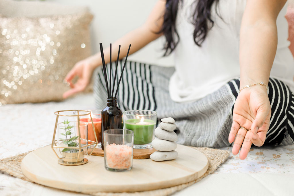 Woman meditating in front of a candle and perfume sticks