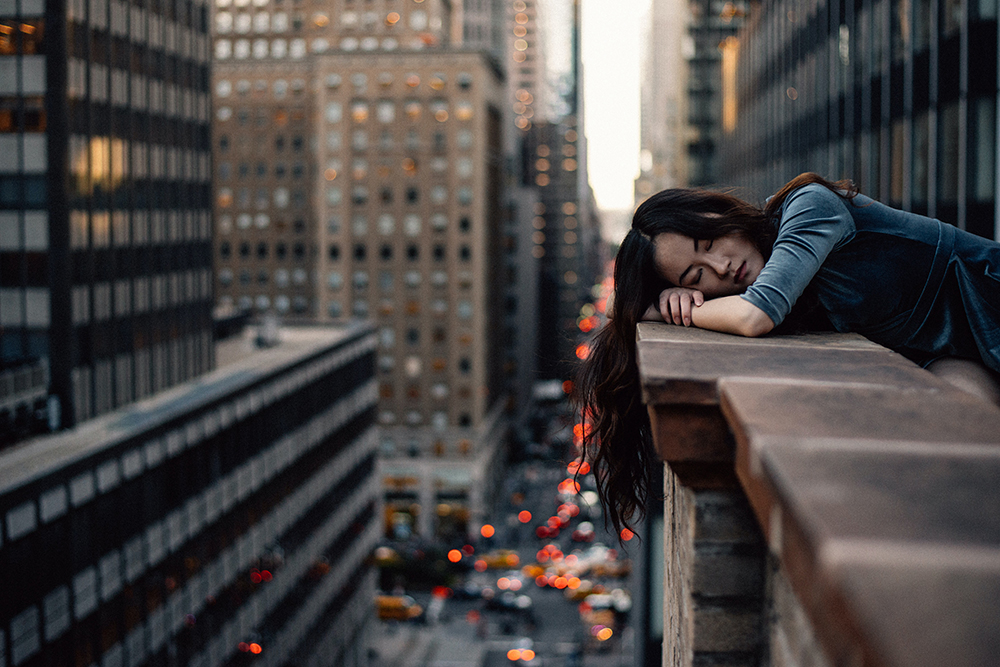 Sleepy lady resting her head on a rooftop ledge