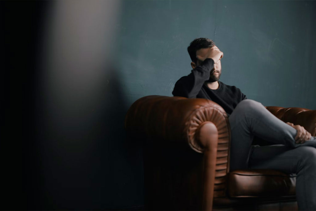 Man in a dim room experiencing a headache