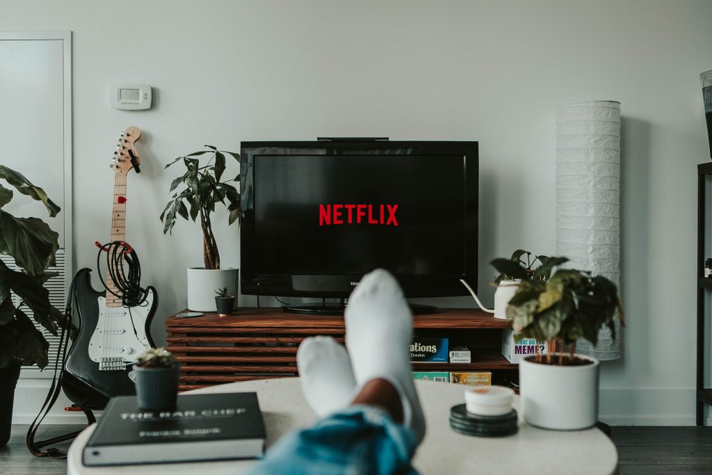 Point of view shot of feet up on the table and Netflix on the TV.